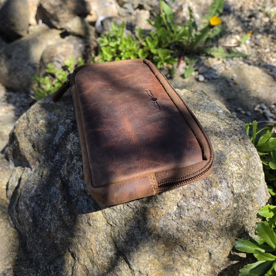 Handytasche aus Leder mit Reißverschluss auf Stein liegend