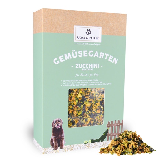 Hellgründe Verpackung aus Pappe mit Sichtfenster, das Zuchhiniflocken zeigt - davor ein Häufchen ausgepackte Zucchiniflocken