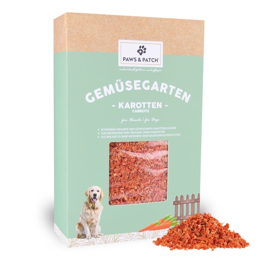 Hellgründe Verpackung aus Pappe mit Sichtfenster, das Karottenflocken zeigt - davor ein Häufchen ausgepackteKarottenflocken
